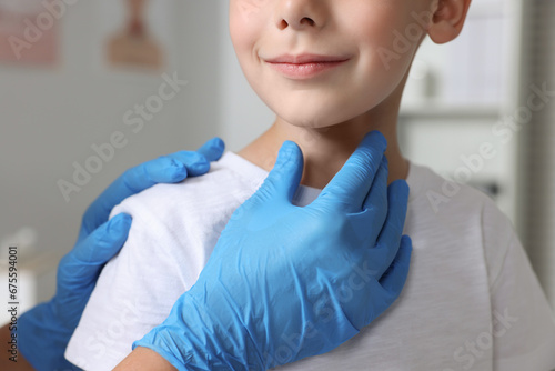 Endocrinologist examining boy's thyroid gland indoors, closeup