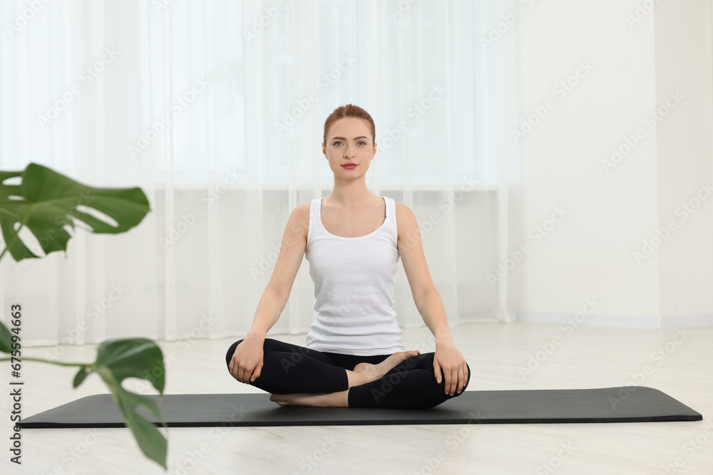 Young woman practicing yoga on mat indoors Young woman practicing yoga on mat indoors