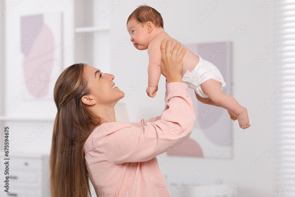 Fototapeta premium Mother holding her cute newborn baby in child's room