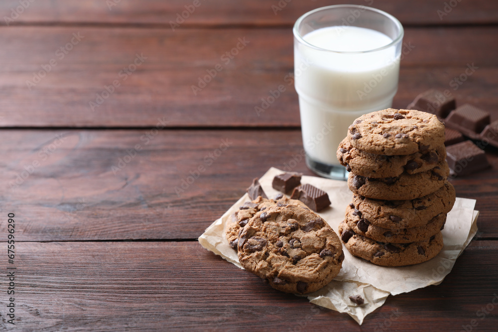 Delicious chocolate chip cookies and glass of milk on wooden table, space for text Delicious chocolate chip cookies and glass of milk on wooden table, space for text