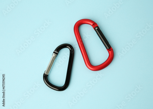 Two metal carabiners on light blue background, flat lay