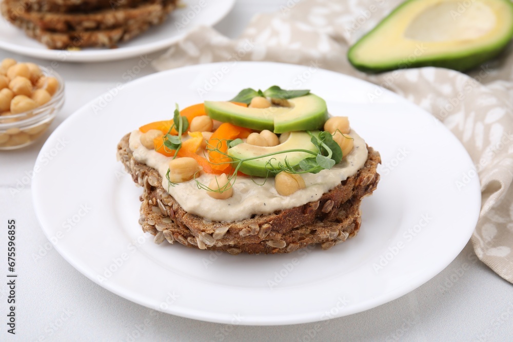 Tasty vegan sandwich with avocado, chickpeas and bell pepper on white table, closeup