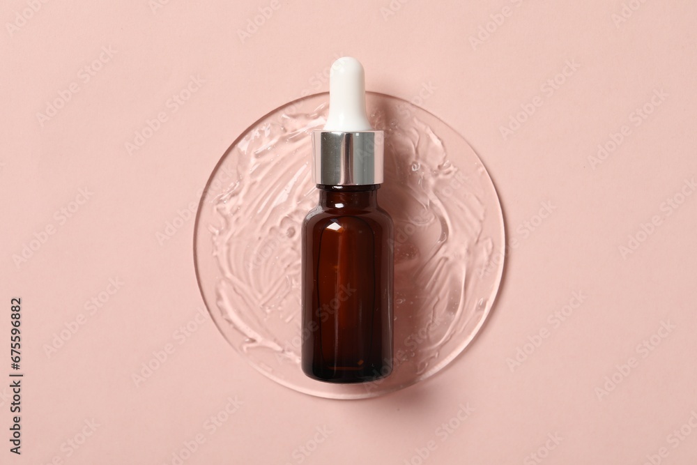 Bottle of cosmetic serum on pink background, top view
