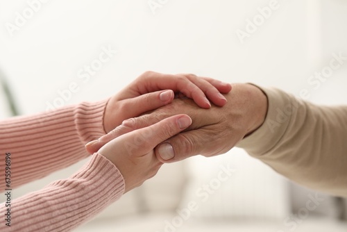 Trust and support. Woman with her dad joining hands on blurred background, closeup