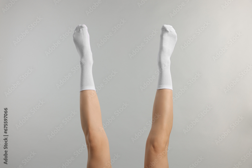 Woman in stylish white socks on light grey background, closeup Woman in stylish white socks on light grey background, closeup