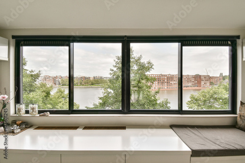 a window with a view of the water and buildings in the distance  as seen from an empty office space