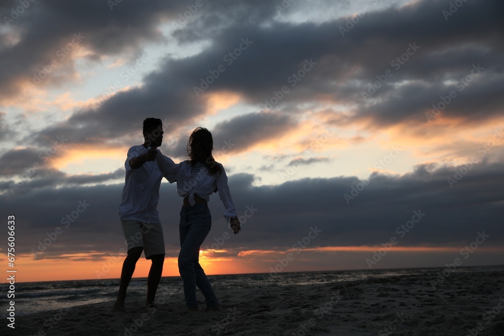 Fototapeta premium Happy couple dancing on beach at sunset