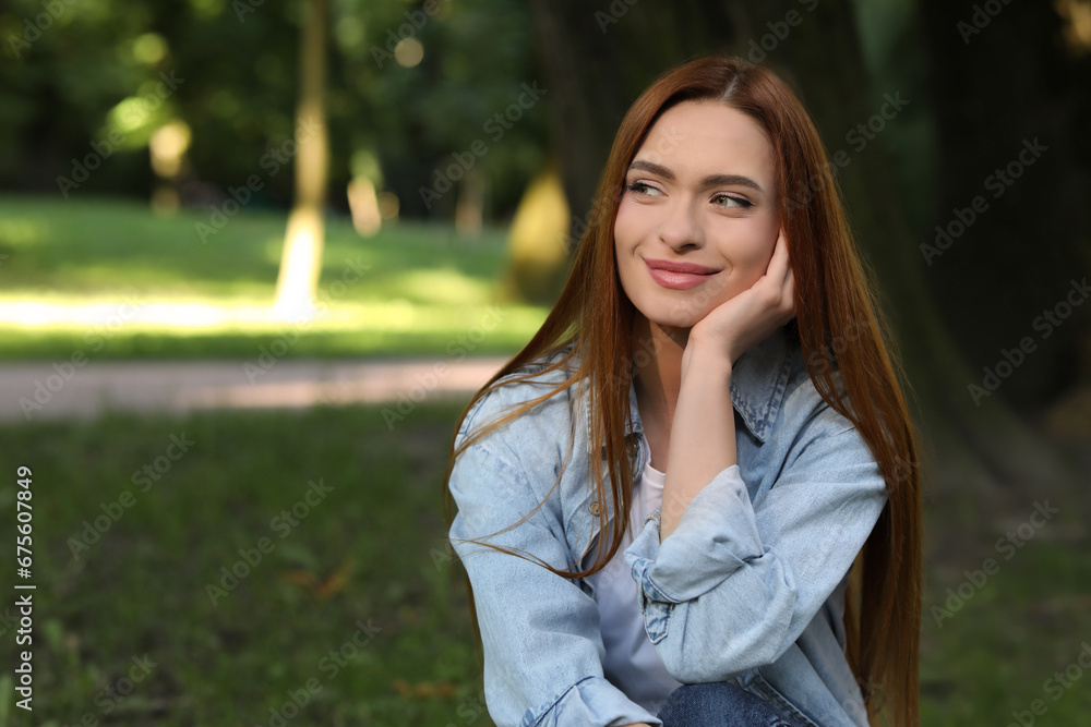 Portrait of beautiful young woman with red hair outdoors. Space for text. Attractive lady posing for camera Portrait of beautiful young woman with red hair outdoors. Space for text. Attractive lady posing for camera