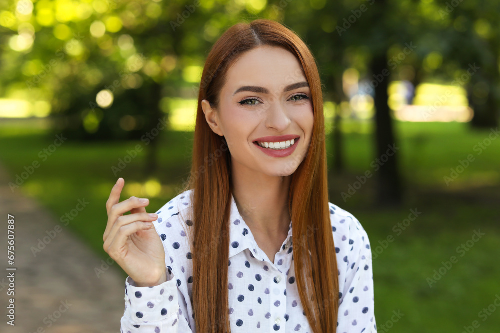 Portrait of charming young woman with beautiful smile in park. Attractive lady posing for camera Portrait of charming young woman with beautiful smile in park. Attractive lady posing for camera