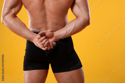 Young man is stylish black underwear on orange background, closeup