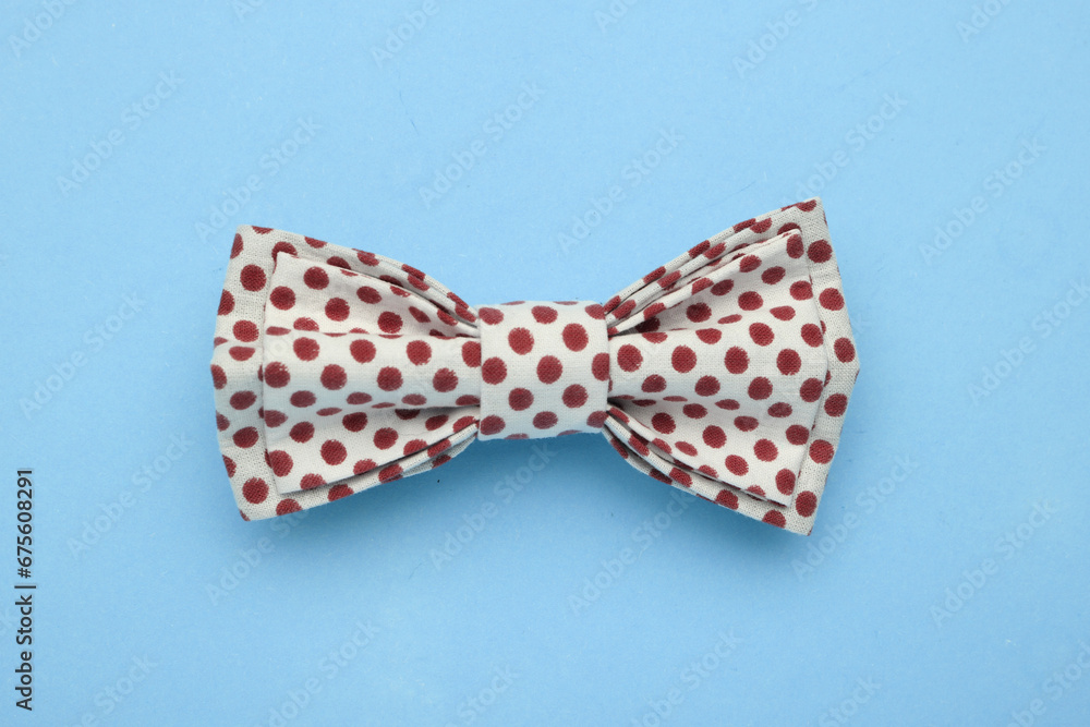Stylish bow tie with dark red polka dot pattern on light blue background, top view Stylish bow tie with dark red polka dot pattern on light blue background, top view