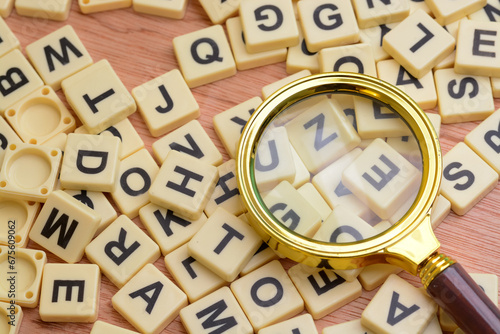 Magnifying glass and scrabble letters. Scrabble is a word game first and foremost. Playing Scrabble will expand your vocabulary and improve your literacy skills. photo