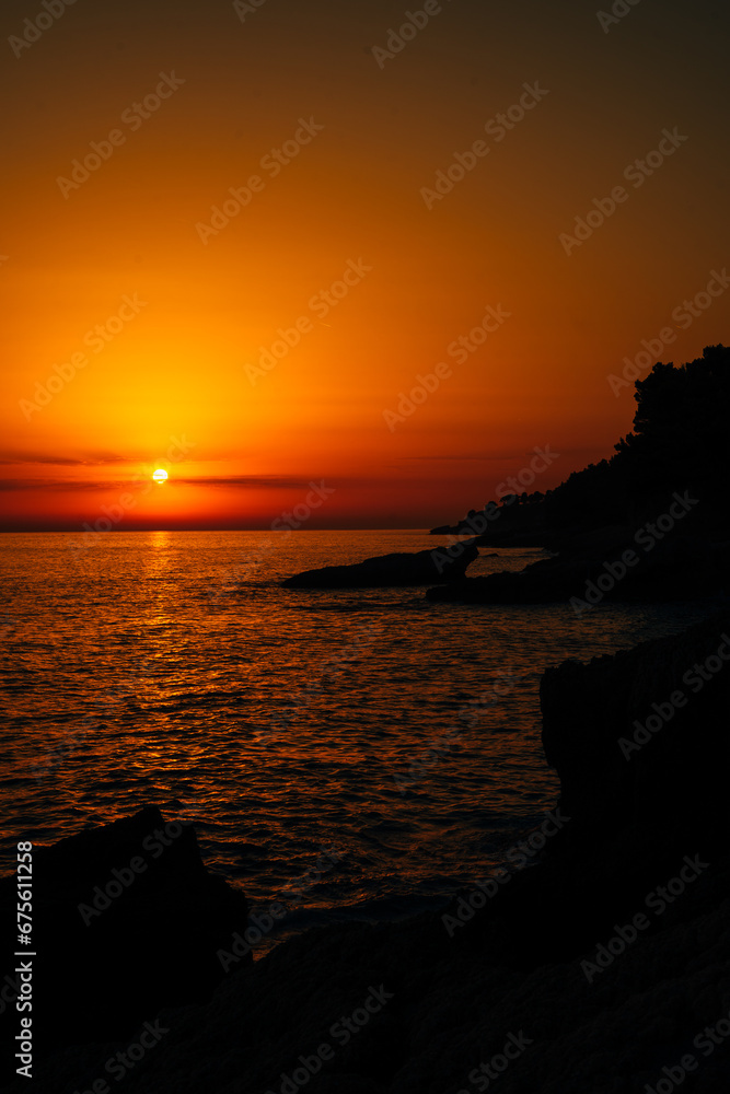 Red sunset over the sea on a rocky shore
