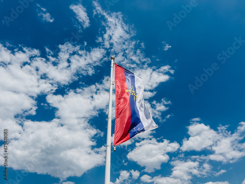 Flag of the Serbian Orthodox Church flutters on a white flagpole photo
