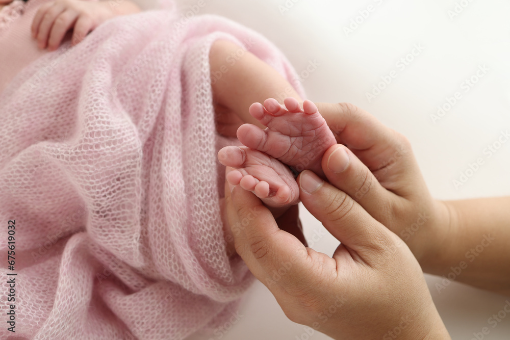 The palms of the father, the mother are holding the foot of the newborn baby in a pink blanket. Feet of the newborn on the palms of the parents. Photography of a child's toes, heels and feet The palms of the father, the mother are holding the foot of the newborn baby in a pink blanket. Feet of the newborn on the palms of the parents. Photography of a child's toes, heels and feet