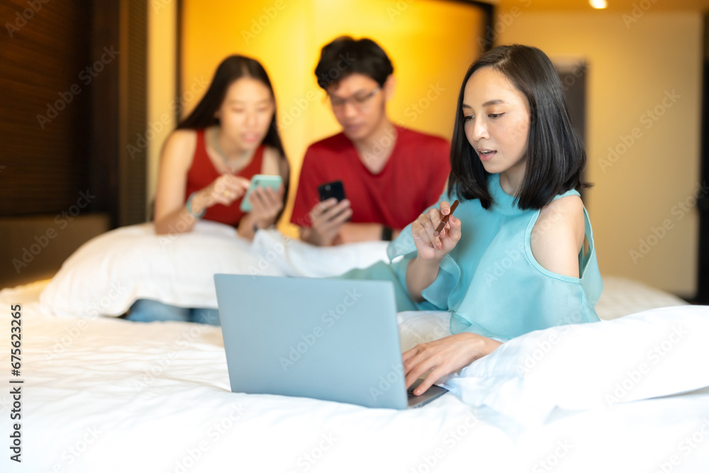 Businesswoman is an Asian boss. Holding a pen and looking at work on a laptop And there are 2 male and female co-workers using smartphones to check company projects related to the online industry. Businesswoman is an Asian boss. Holding a pen and looking at work on a laptop And there are 2 male and female co-workers using smartphones to check company projects related to the online industry.