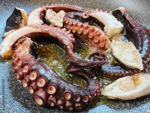Pieces of octopus tentacles boil in oil in a frying pan