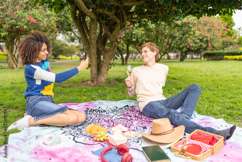 Multiracial couple taking photos and enjoying a romantic picnic