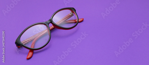 Stylish eyeglasses on purple background with space for text