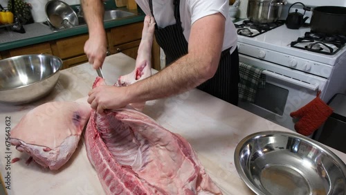 Amateur butcher or chef portioning hog sliced in half into smaller pieces, first cutting front leg. photo