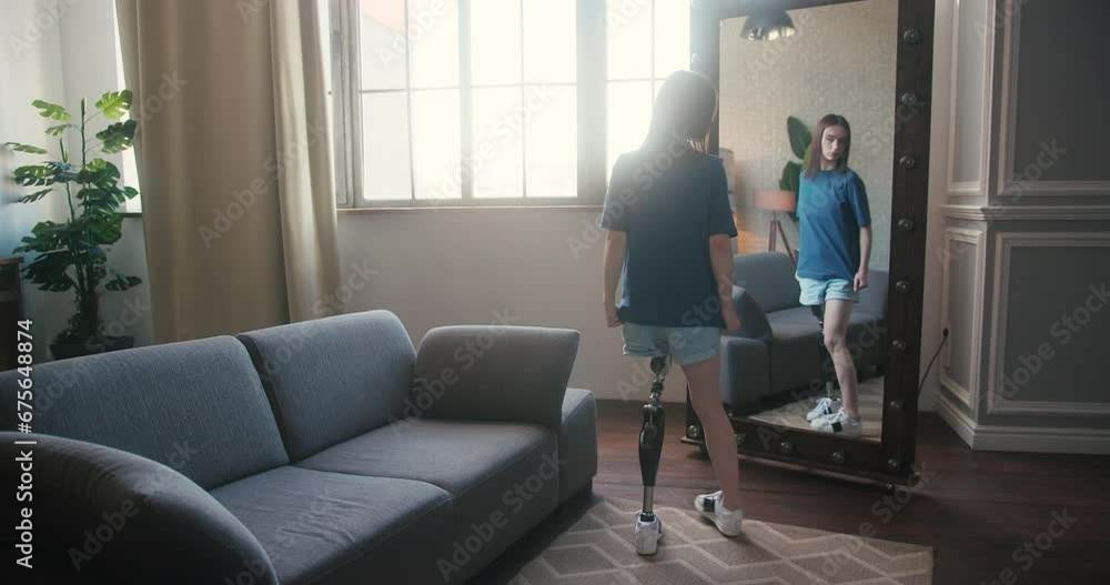 Young woman takes moment to inspect artificial limb in mirror Young woman takes moment to inspect artificial limb in mirror