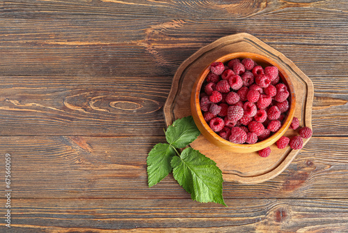 Bowl and board with fresh ripe raspberries on wooden background