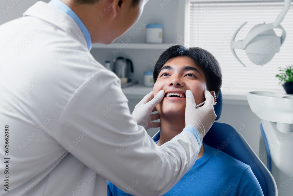 Young man getting dental checkup at dentistry. Dentist using dental equipment for examination of teeth of patient. Young man getting dental checkup at dentistry. Dentist using dental equipment for examination of teeth of patient.