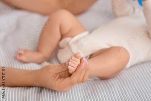 Mother massaging her baby's foot in bedroom, closeup