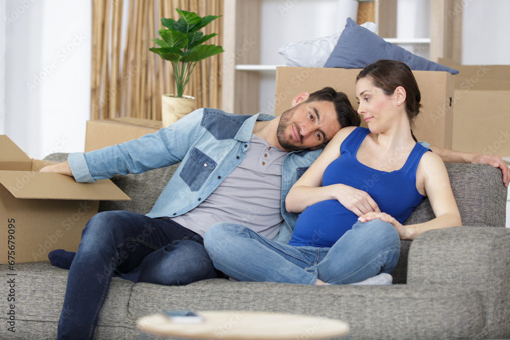 Fototapeta premium upset pregnant couple lost apartment things packed in boxes