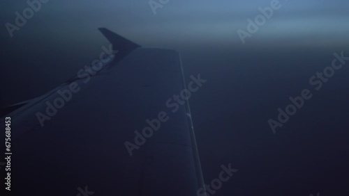 Against the background of the twilight sky, the white wing of an airplane flying over a foggy field. The concept of air travel and transport. High quality 4k footage