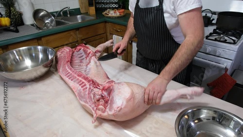 Preparing half sliced butchered hog placed on kitchen table to be cut or portioned into pieces. photo