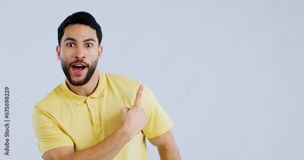 Man, portrait and pointing up in surprise on mockup for deal, advertising or marketing against a gray studio background. Shocked or surprised male person or model showing notification, alert or sale Man, portrait and pointing up in surprise on mockup for deal, advertising or marketing against a gray studio background. Shocked or surprised male person or model showing notification, alert or sale