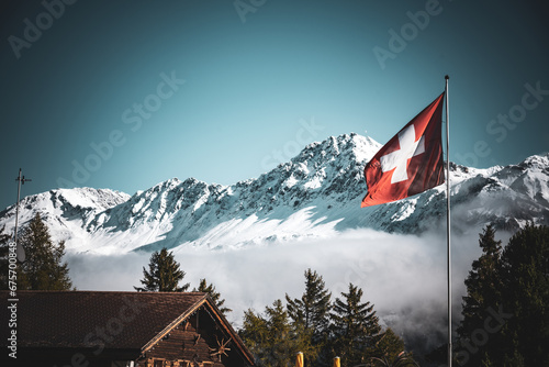 Wechsel der Jahreszeiten, vom Herbst zum Winter in den Schweizer Alpen mit Schweizer Fahne, Lenzerheide photo
