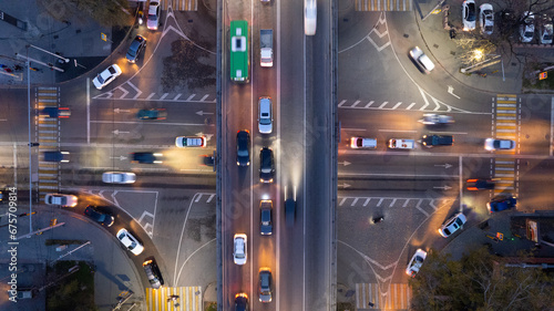 A busy intersection with a lot of cars, buses and trucks. Aerial view from the drone on the night road, the city and pedestrians. Lights and headlights are shining. A traffic jam has formed. Almaty