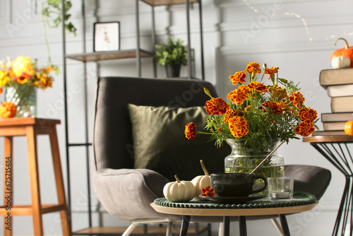 Beautiful autumn flowers, cup of drink and pumpkins on coffee table indoors, space for text