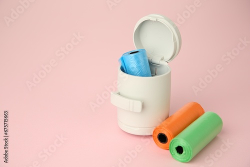Dog waste bags and dispenser on pink background. Space for text