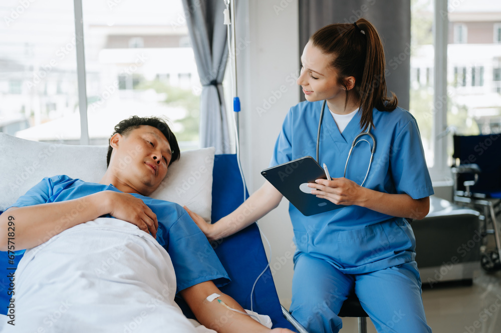 Friendly Female Head Nurse Making Rounds does Checkup on Patient Resting in Bed Friendly Female Head Nurse Making Rounds does Checkup on Patient Resting in Bed
