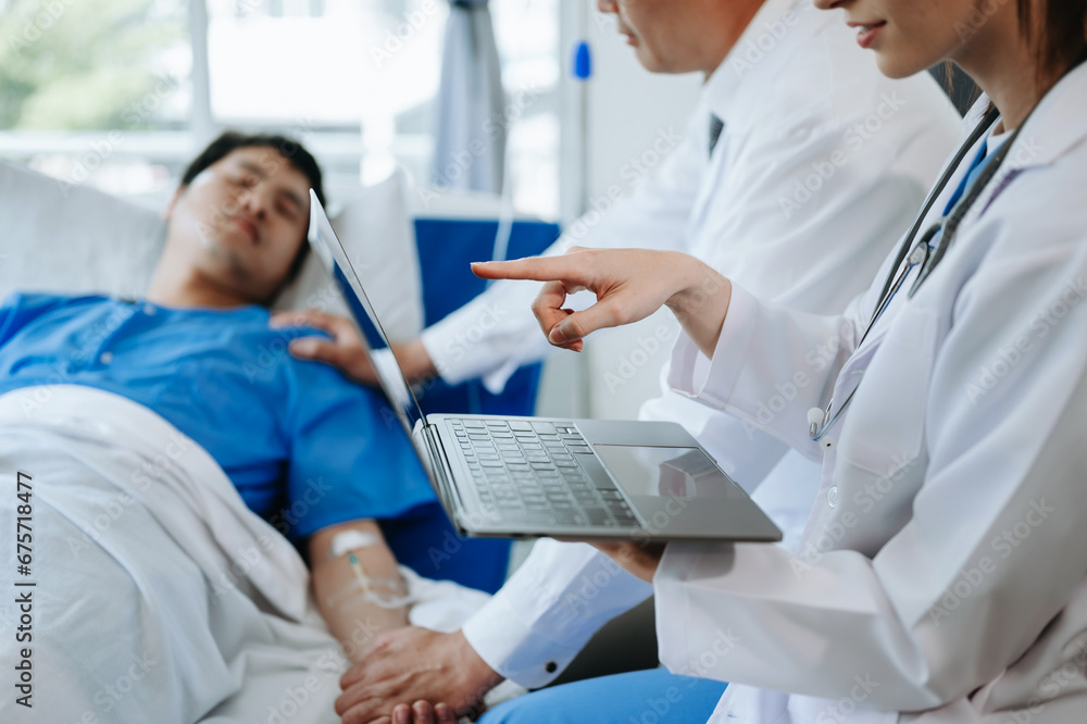 Fototapeta premium Two doctors talking to a patient lying in his bed with receiving saline solution in a hospital