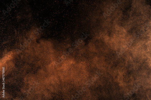 Orange powder explosion on black background. Flame cloud. Yellow dust explode. Freeze motion paint Holi.
