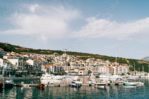 Colorful houses on the coast of Lustica bay marina with moored yachts. Montenegro