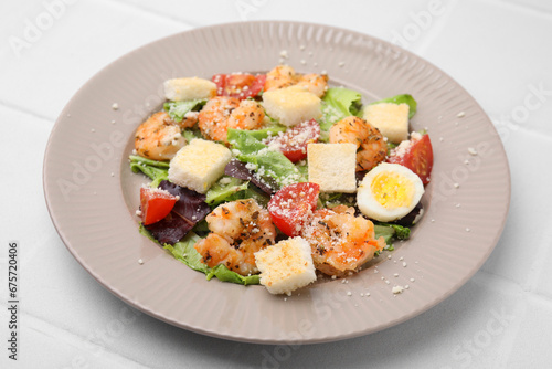 Delicious Caesar salad with shrimps on white tiled table, closeup