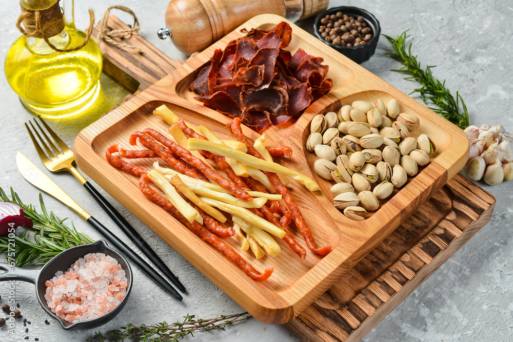 Snacks for beer. Pistachios, cheese, sausages and dried meat. On a wooden plate. Rustic style. Snacks for beer. Pistachios, cheese, sausages and dried meat. On a wooden plate. Rustic style.
