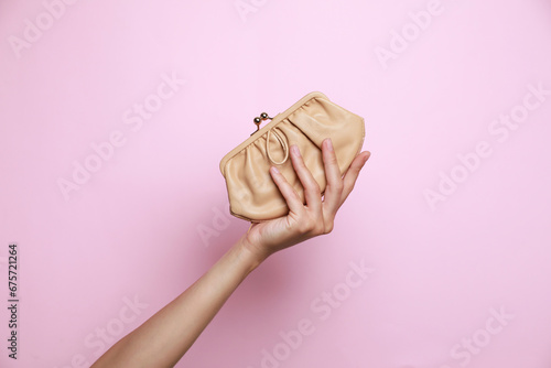 Woman holding leather purse on pink background, closeup