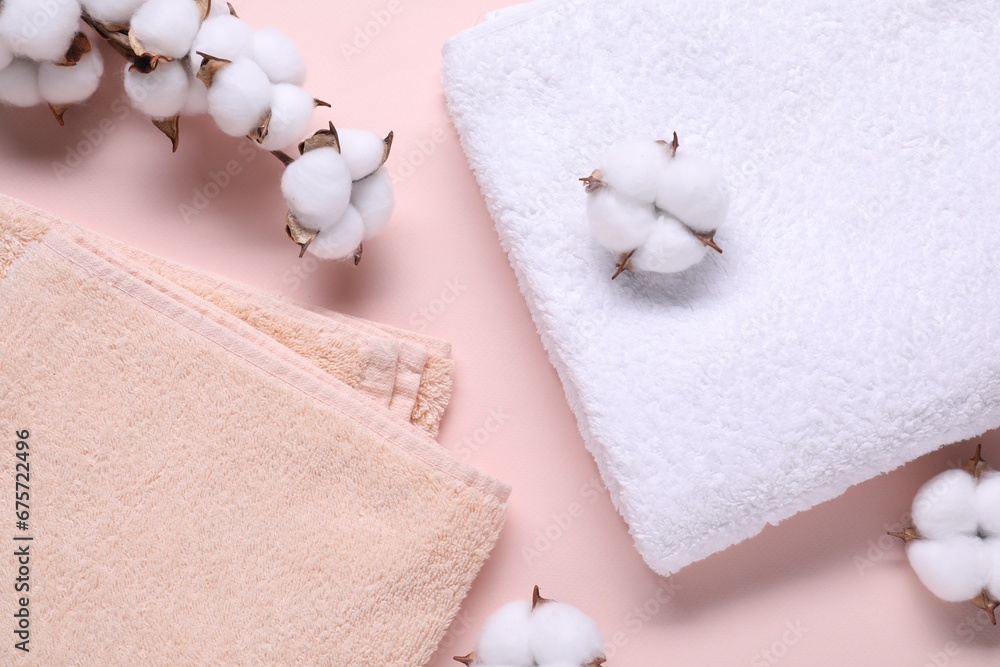Cotton branch with fluffy flowers and terry towels on beige background, flat lay Cotton branch with fluffy flowers and terry towels on beige background, flat lay