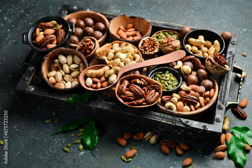 Assortment of nuts in a wooden box on a black background - healthy snack. Top view. Copy space