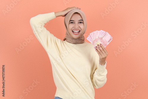 howing cash money in Indonesian rupiah banknotes and holding head. photo