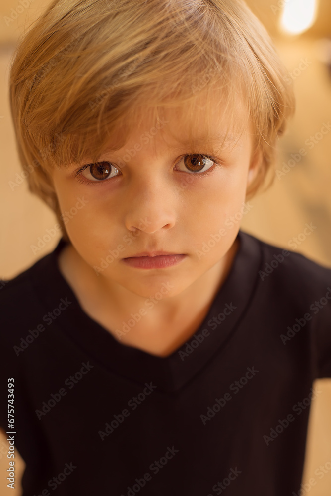 a thoughtful blond boy with big eyes in a black jacket on a yellow background a thoughtful blond boy with big eyes in a black jacket on a yellow background
