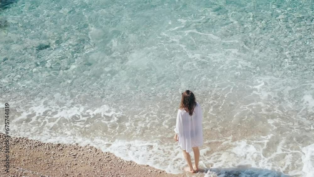 Aerial view of a young woman walking the beach by the clear azure water. The Mediterranean Sea in Turkey. Aerial view of a young woman walking the beach by the clear azure water. The Mediterranean Sea in Turkey.