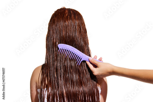 Female hand brushing long wet hair of a girl against white studio background. Taking care after hair look. Concept of beauty, hair care, treatment, natural cosmetics. Copy space for ad