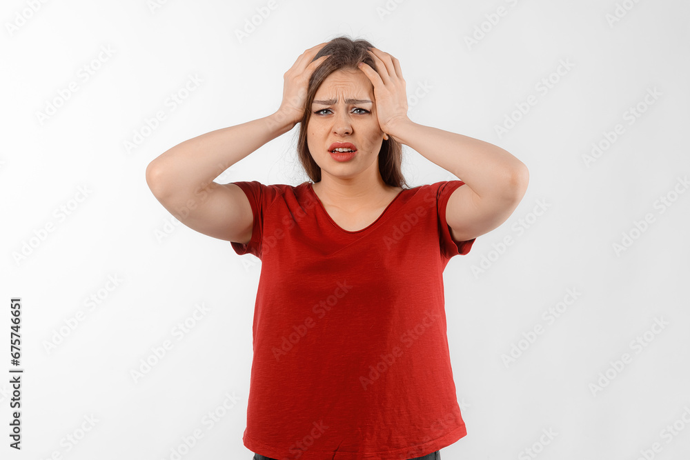 Portrait of a young woman has a headache, migraine. Beautiful woman tired at work. Winsome female model in red t shirt posing over white studio background Portrait of a young woman has a headache, migraine. Beautiful woman tired at work. Winsome female model in red t shirt posing over white studio background